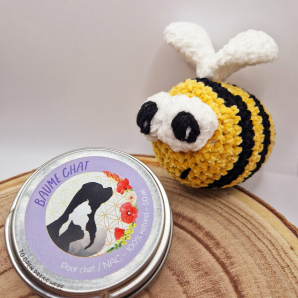Une boite en fer de baume de soin pour chat Natur'O'Poil avec une peluche abeille au crochet