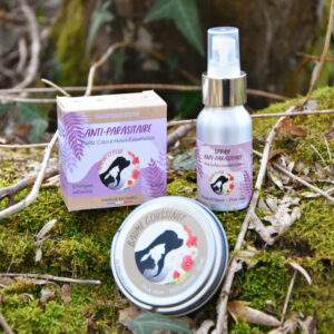 Ensemble de produits pour chien Natur'O'Poil posés en pleine forêt : boite en carton avec savon solide, boite en fer avec baume de soin et flacon spray